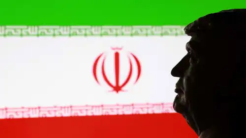 الرئيس الأمريكي دونالد ترامب إلى حانب علم إيران