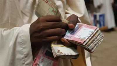 سوداني يحمل أوراقا نقدية من عملة بلاده