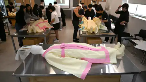 يُلبس طلابٌ دميةً بقماش جنازة كوري تقليدي خلال دورةٍ تدريبيةٍ في إدارة الجنازات