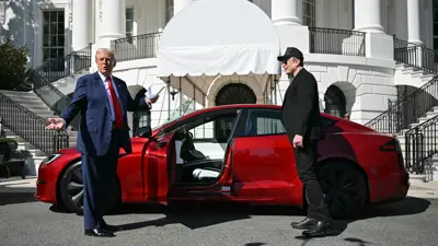 الرئيس ترامب وإيلون ماسك بجانب سيارة تسلا 