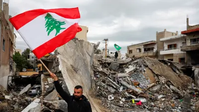 لبناني يرفع علم بلاده وسط الدمار