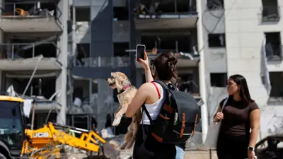 سيدتان تصوران مبنى تضرر بفعل القصف الإيراني