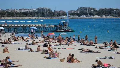 يستمتع الناس بأشعة الشمس على شاطئ كرويزيت في كان، فرنسا