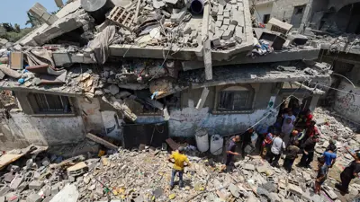 أشخاص يتفقدون الأضرار في موقع غارة إسرائيلية استهدفت منزلاً في مخيم النصيرات للاجئين الفلسطينيين في وسط قطاع غزة