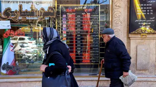 رجل وامرأة يمران أمام محل صرافة عملات، طهران، 3 مارس 2025.