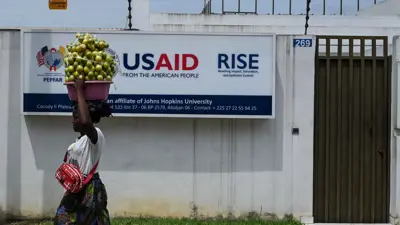 بائعة متجولة تمشي أمام مكتب الوكالة الأمريكية للتنمية الدولية (USAID) في أبيدجان