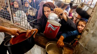 فلسطينيون يتجمعون لتلقي الطعام الذي تطبخه إحدى المطابخ الخيرية