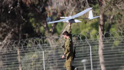 جندي إسرائيلي يحمل طائرة مسيّرة