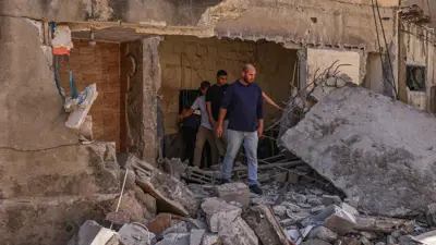 فلسطينيون أمام منزل دمرته مسيرة إسرائيلية في الضفة 