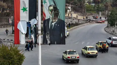 صورة ممزقة للأسد في دمشق