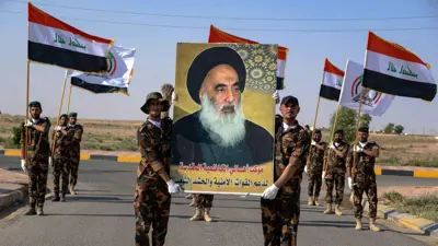 عناصر من الحشد الشعبي يرفعون صورة السيستاني
