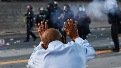 رجل يرفع يديه بينما يطلق الضباط الغاز المسيل للدموع في لوس أنجلوس