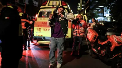 إسرائيلي يحمل سلاحاً رشاشاً في موقع تنفيذ عملية الطعن