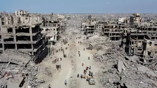 فلسطينيون يسيرون بين أنقاض المباني المدمرة في غزة