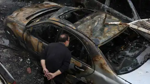 شخص ينظر إلى سيارة محترقة بالهجمات الإسرائيلية على بيروت