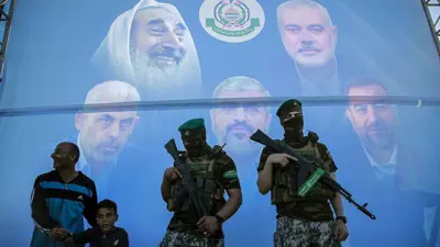 مقاتلان من حماس أمام جدارية لقادتها