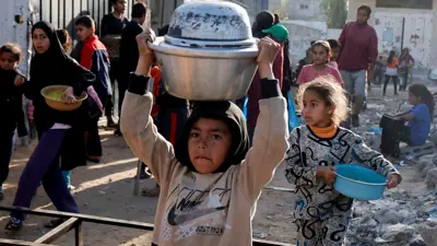 أطفال فلسطينيون يتلقون طعامًا مطبوخًا في مطبخ خيري