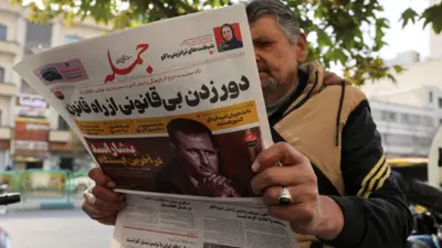 غلاف صحيفة إيرانية يقرأها مواطن تبرز سقوط الأسد