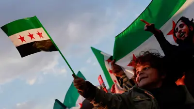 طفل يرفع علم سوريا الجديد