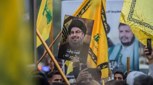 أنصار مليشيا حزب الله يرفعون علم الحزب وصورة حسن نصر الله