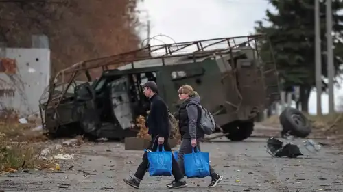 أوكرانيان يسيران بجوار عربة عسكرية مدمرة في "أوبلاست دونيتسك" 