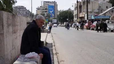 رجل يجلس على قارعة الطريق في اللاذقية بعد أحداث الساحل 