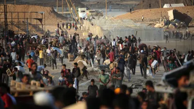 فلسطينيون يتجمعون عند نقطة توزيع مساعدات بالقرب من مخيم النصيرات للاجئين في وسط قطاع غزة