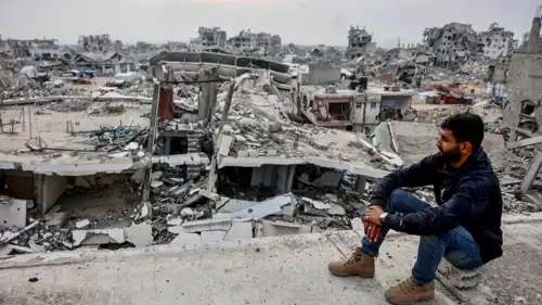 فلسطيني يجلس على مبنى متضرر بحي تل الهوى