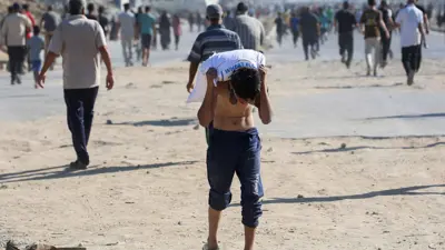 فلسطيني يحمل حقيبة مساعدات غذائية في دير البلح، وسط قطاع غزة