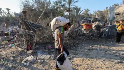 رجل فلسطيني يحمل أمتعته في موقع غارة إسرائيلية ألحقت أضرارًا بمخيم للنازحين، وسط قطاع غزة