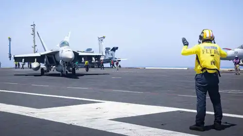 عامل يوجه مقاتلة أمريكية على متن حاملة طائرات